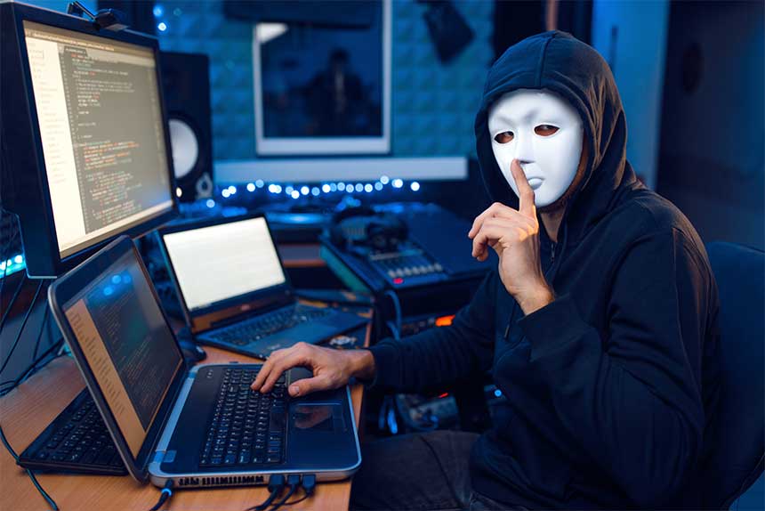 Un hacker avec masque devant des ordinateurs